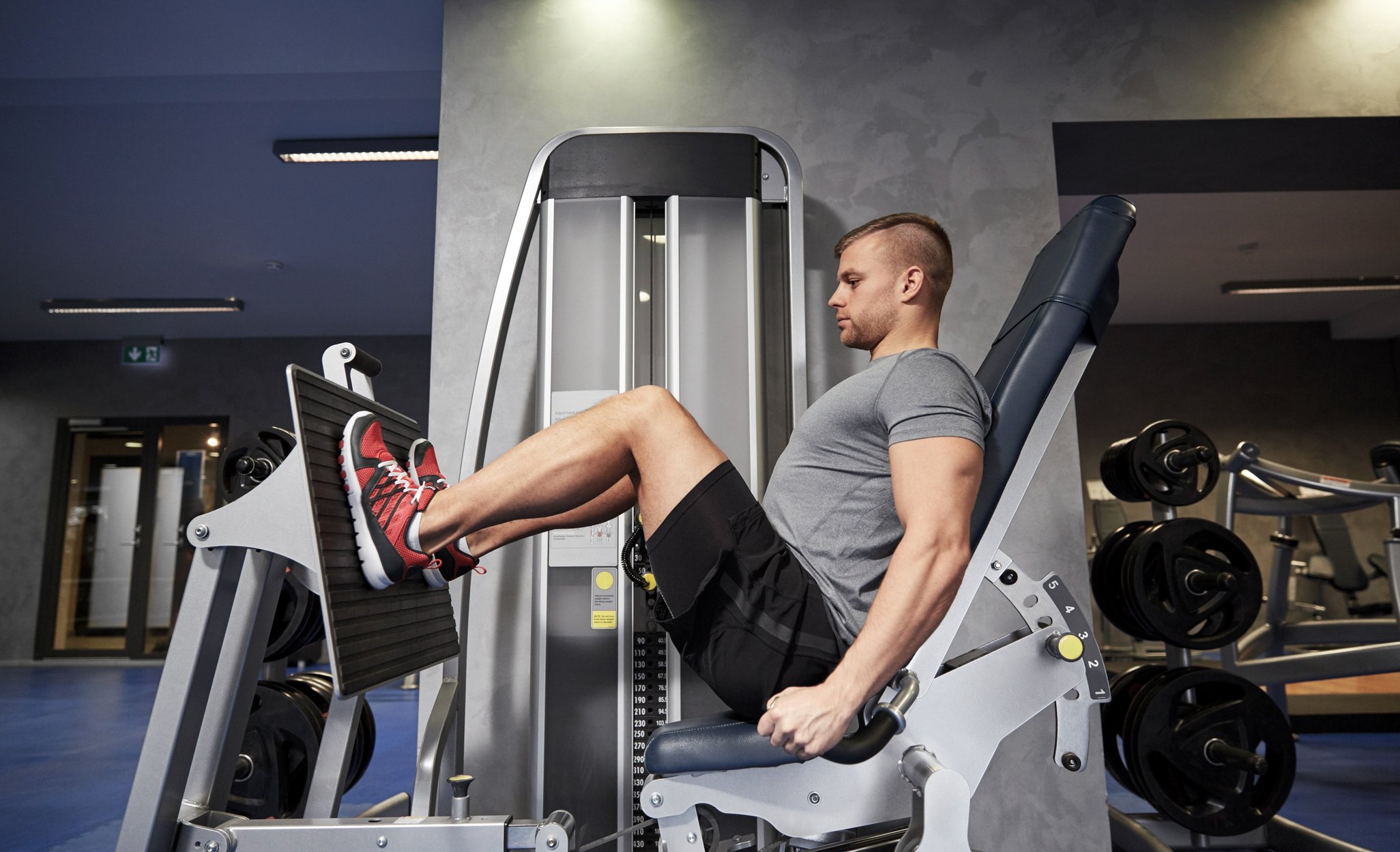 Man Flexing Leg Muscles on Gym Machine